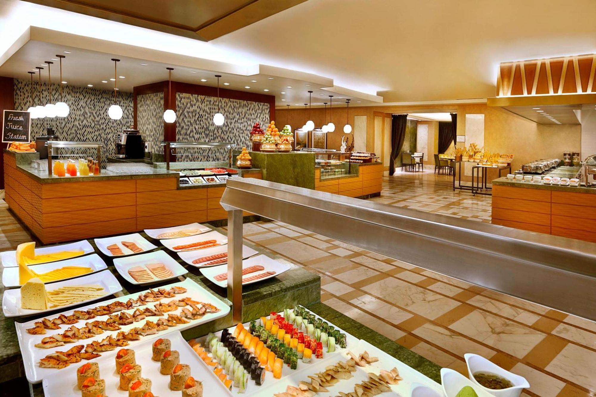 Jabal Omar Marriott Hotel Makkah Mecca Exterior photo The photo depicts a buffet-style restaurant setup. There are various food displays featuring an array of colorful dishes, including sushi, seafood, and other appetizers, arranged artfully on white platters. The dining area is spacious and well-lit, w